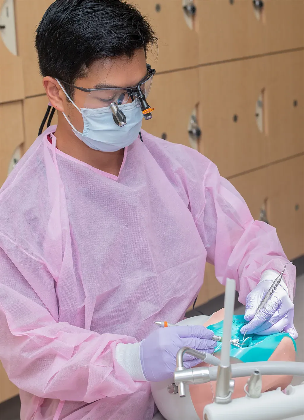 A dental medicince student wearing pink scrubs practicing skills in the Oral Health Center