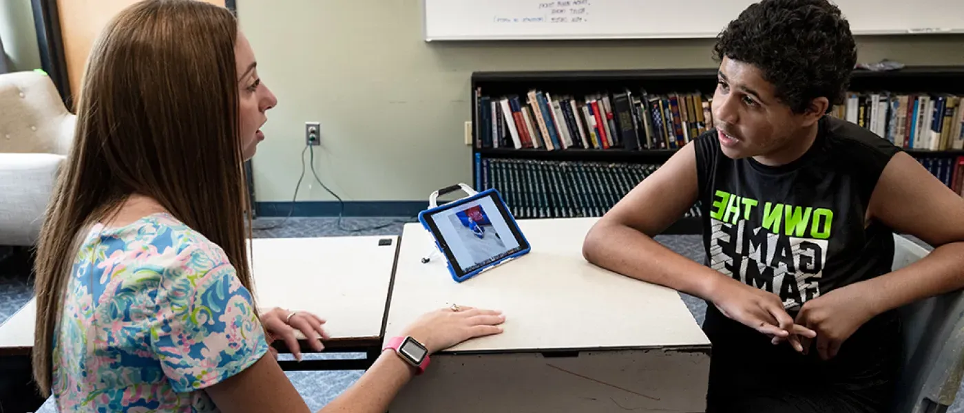 A U N E student shows an elementary school student how to use an i-pad